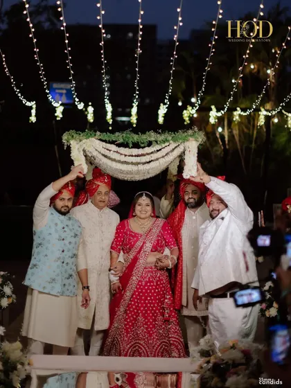 The bride under a traditional floral chadar, held by her family, a beautiful and emotional moment during the wedding ceremony.