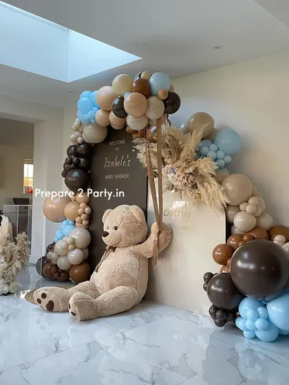 A side view of the "We Can Bearly Wait" baby shower decor, showing the arrangement of the backdrops and the full arc of the brown, beige, and blue balloons.