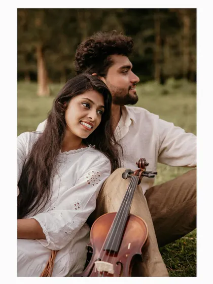 A quiet moment of rest during a pre-wedding shoot, with the couple and a violin in a beautiful meadow.