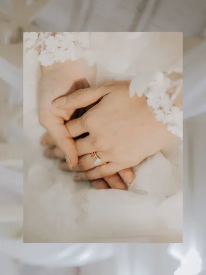 A detailed shot of the bride's hands, showcasing her wedding ring and the delicate lace of her gown.