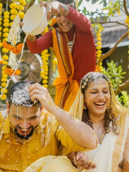 Laughter erupts as a friend pours water over the couple during their haldi, a classic moment of fun and games.