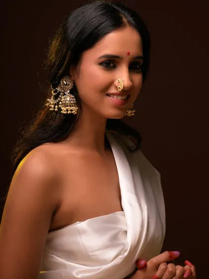 A beautiful and serene ethnic portrait. The model's traditional jewelry and gentle expression are highlighted by warm, soft lighting.