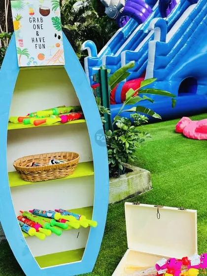 A surfboard-shaped shelf holding water guns for guests to 'grab one & have fun'.