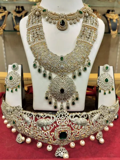 A complete American diamond and emerald bridal set, including a unique vaddanam with elephant motifs.