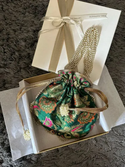 A beautiful brocade potli being placed in an elegant gift box. This is an example of how I package individual items to make them feel like a luxurious present.