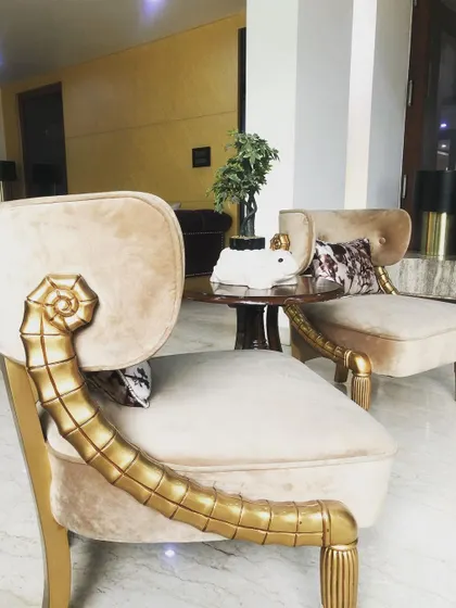 These unique chairs feature an ornate, hand-carved armrest with a gold finish that contrasts beautifully with the soft beige upholstery. They are true statement pieces, designed for a client who wanted something that blends classic carving with modern comfort.