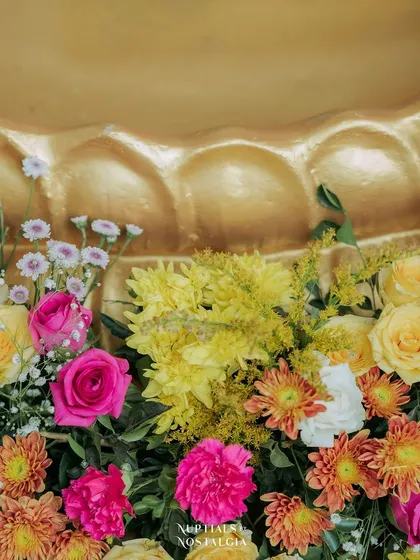 A close-up of a colorful floral arrangement against a golden urli.