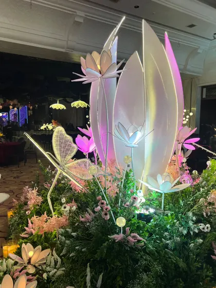 A magical centerpiece for our enchanted sangeet, featuring glowing lotus and butterfly sculptures nestled in a bed of lush greenery and flowers.