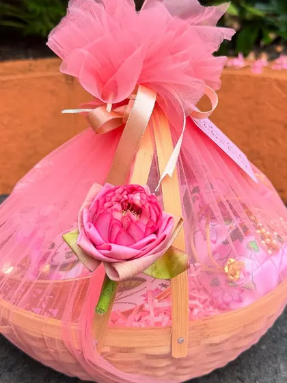 A close-up of the elegantly wrapped return gift basket, featuring pink tulle and a delicate lotus flower accent. The presentation is as important as the gift itself.