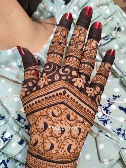 A close-up of a guest's hand, showing a simple yet beautiful vine pattern.