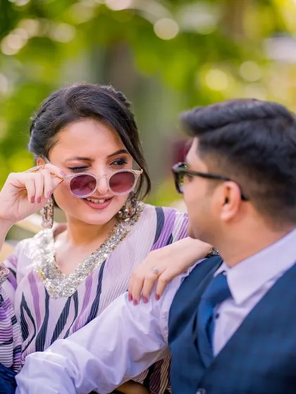 A cool and candid close-up. The bride-to-be playfully adjusts her sunglasses, sharing a fun, flirty moment with her partner in this stylish, modern shot.
