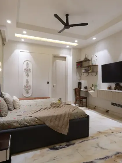 This guest bedroom at Harmony House was designed for ultimate comfort, with soft beige tones, an intricately molded bed back, and a cozy sitting area.