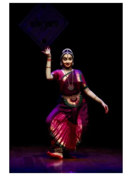 A graceful pose from a performance at Aikyam 2024, with the stage backdrop adding to the ambiance.