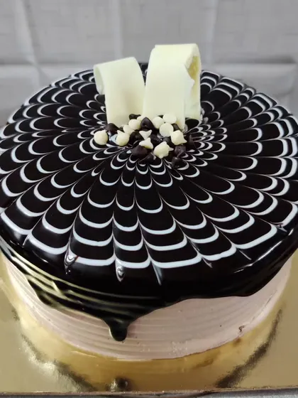 A classic chocolate truffle cake with a beautiful spider-web pattern. The white chocolate curls on top complete this elegant look.