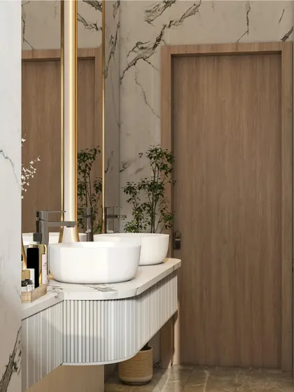 This bathroom vanity design combines a fluted wood-textured base with a clean white countertop and vessel sinks. The large, backlit mirror and marble-patterned wall tiles add a touch of modern luxury.
