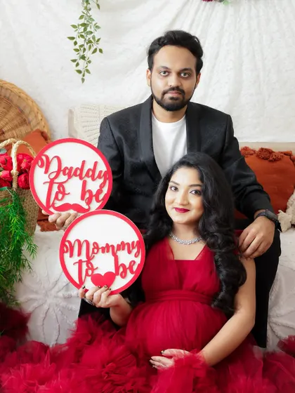 A classic announcement photo with "Mommy to be" and "Daddy to be" signs. The couple looks directly at the camera, sharing their happy news.