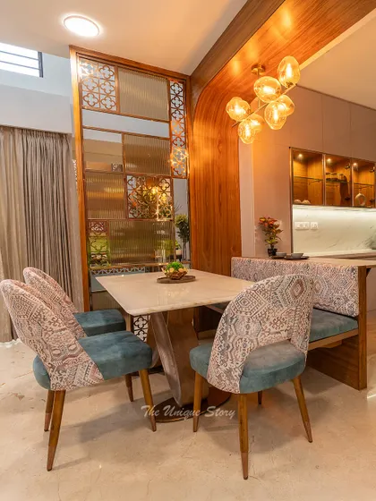 A detail of the dining setup, showing the patterned upholstery of the chairs and the elegant wooden partition with jali work. This blend of textures and traditional motifs is a hallmark of our Indian contemporary style.