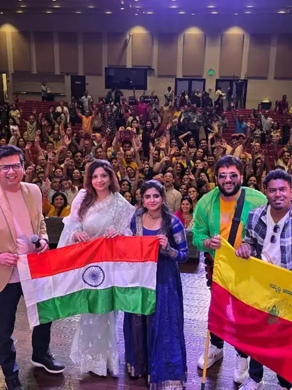 The whole team on stage in America, proudly holding the Indian and Kannada flags. We carry our roots with us wherever we go.