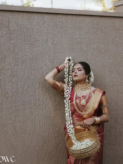 The bride poses with a basket of jasmine flowers, her expression serene and beautiful.