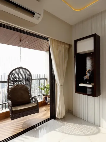 A cozy corner of a living room featuring a hanging wicker chair on the balcony. This detail shows how I extend the living space outdoors, creating a perfect spot for relaxation.