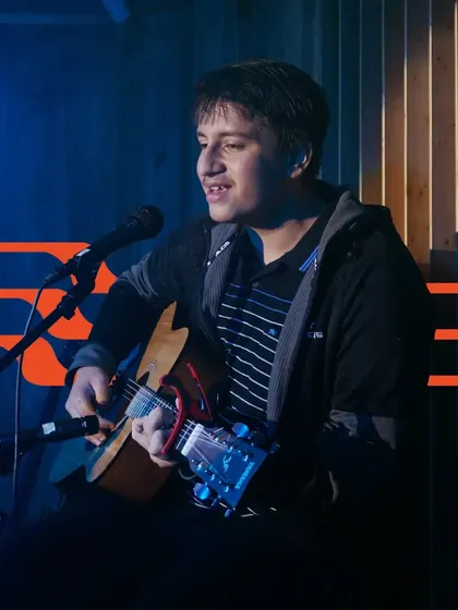 A student sings and plays guitar, showcasing the singer-songwriter skills we help develop. We support students in both their technical and creative journeys.