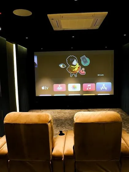 The view from the back row, showing how every seat gets a perfect, centered view of the screen. The Apple TV interface demonstrates the smart, user-friendly technology integrated into the system.