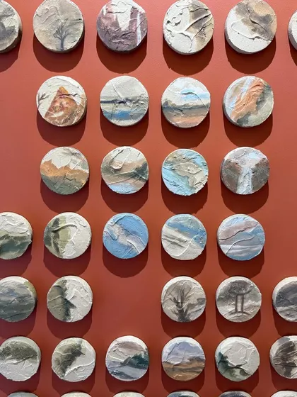 A closer look at a section of the 100-piece installation. You can see the variety of scenes, from mountains and forests to seascapes, all in a cohesive color palette.