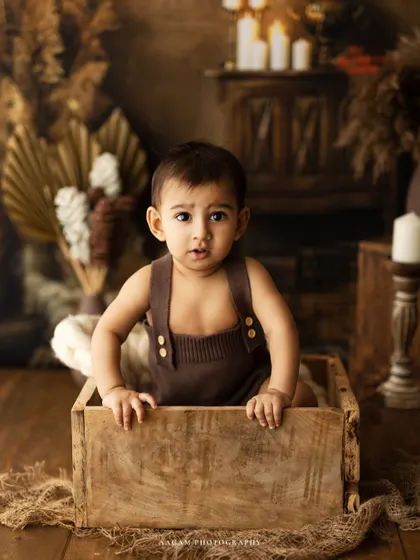 A one-year-old boy peeking out of a rustic wooden crate. This "It's Fun to be One" session is all about capturing the playful spirit of a new toddler.