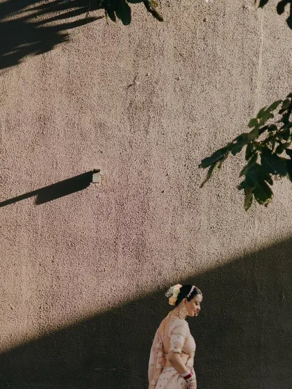 An artistic shot of the bride walking in the shadows, with only a sliver of sunlight illuminating her, creating a dramatic and thoughtful portrait.