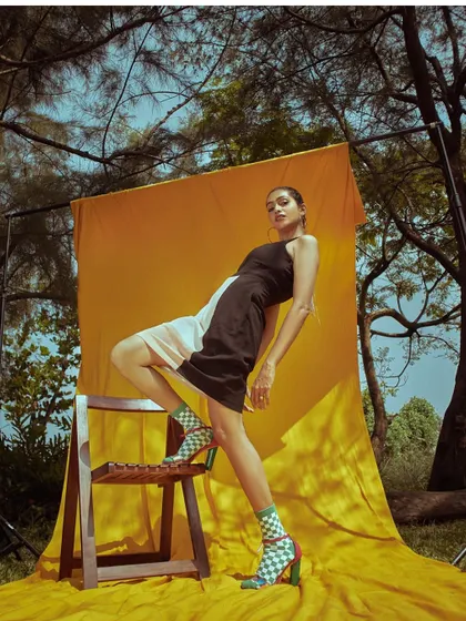 A dynamic pose using the chair as a prop, showcasing the model's flexibility and the outfit's versatility.