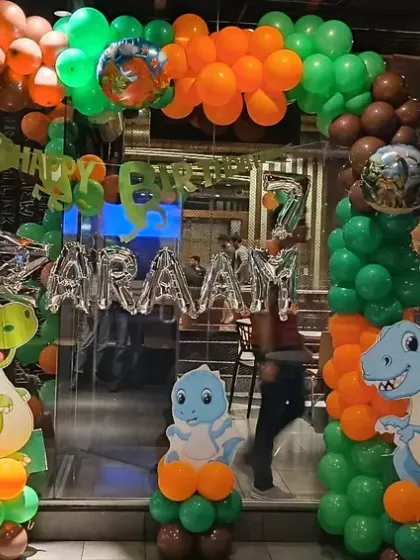 Another angle of the dinosaur party entrance, showing the full balloon arch and character stands.