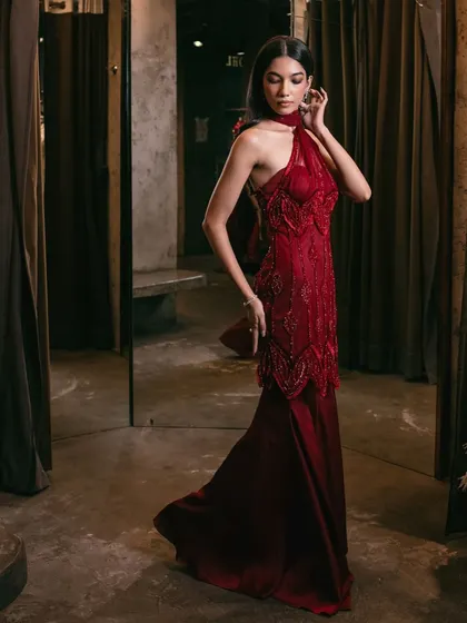A breathtaking crimson-hued sharara, adorned with exquisite embellishments and featuring a striking one-shoulder design with an attached drape.
