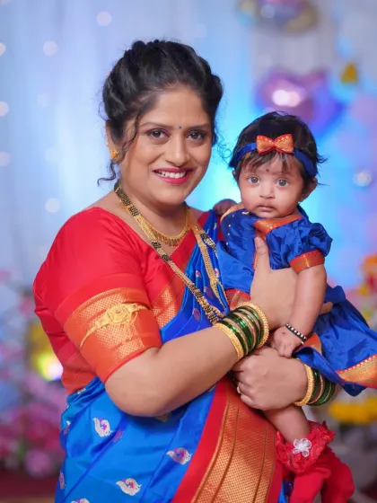 A heartwarming portrait of a mother and her baby at the naming ceremony. Both are dressed in beautiful traditional outfits, capturing a key moment from this important family function.
