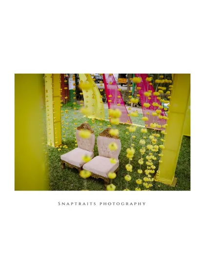 A duplicate of an artistic shot of the Haldi ceremony decor, focusing on the empty chairs waiting for the couple, with marigold garlands creating a beautiful foreground.