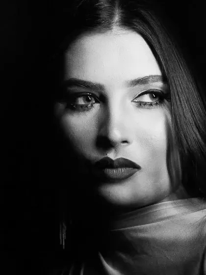 This shot uses dramatic, low-key lighting to create a film noir effect, with the makeup defining the visible features.