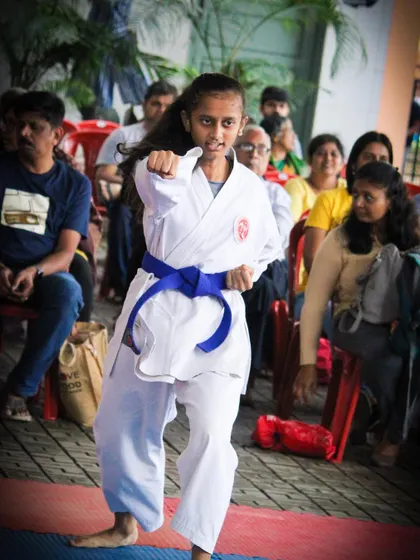 A student performs her Kata routine in front of an audience, demonstrating the focus and sharp technique required for competitive forms.