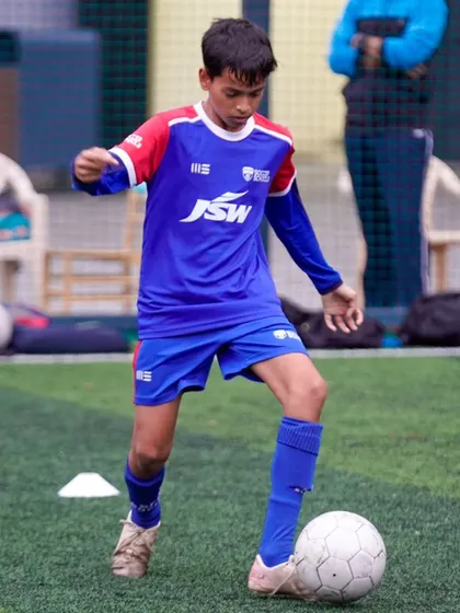 A young player shows determination as he controls the ball. We nurture a mindset of continuous improvement and hard work.