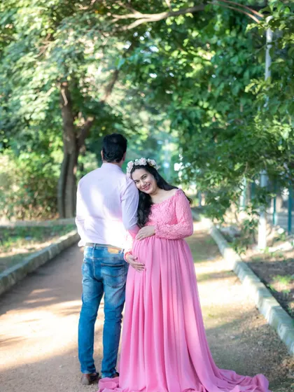 A sweet photo of a couple on a park path. The mom-to-be leans against her partner, both looking happy and relaxed.