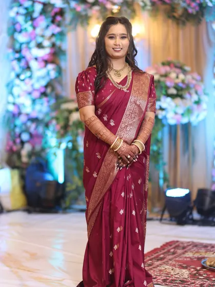 A full-view of the bride's engagement look in a beautiful maroon saree. The makeup, hair, and saree draping come together for a polished and elegant appearance.