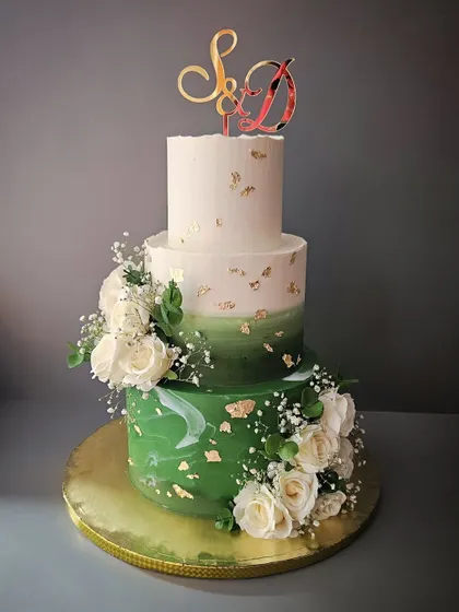 Grand in Green. A three-tier vanilla strawberry cake for a wedding or reception. The bottom tier has a green marble effect, complemented by white roses and gold leaf.