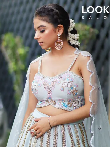A dreamy, ethereal look perfect for a Diwali party. The makeup is soft and luminous, paired with a braided hairstyle and floral accents to complement the pastel blue lehenga.