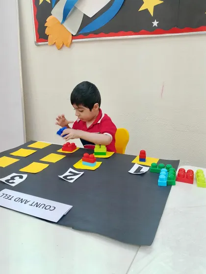 Problem solving in action. This student is figuring out the correct number of blocks for each numeral, demonstrating how our activities encourage independent thinking and mathematical reasoning.