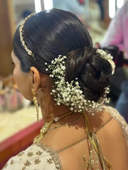 A full view of the sleek bridal bun, adorned with a semi-circle of fresh baby's breath. This is a clean, sophisticated style for the modern bride.