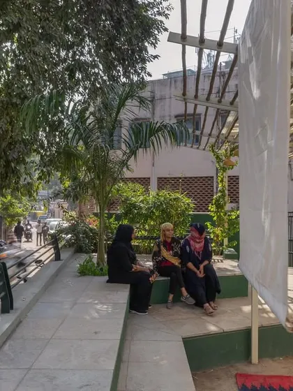 Women relaxing on the integrated seating at Basera Plaza, which overlooks the adjacent street. This design promotes "eyes on the street," enhancing safety and fostering a sense of community ownership.