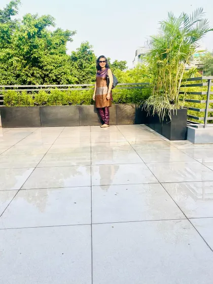 A full view of the newly made rooftop garden in GK, Delhi. The design is clean and modern, using large tiles and sleek black planters to create a sophisticated urban space.
