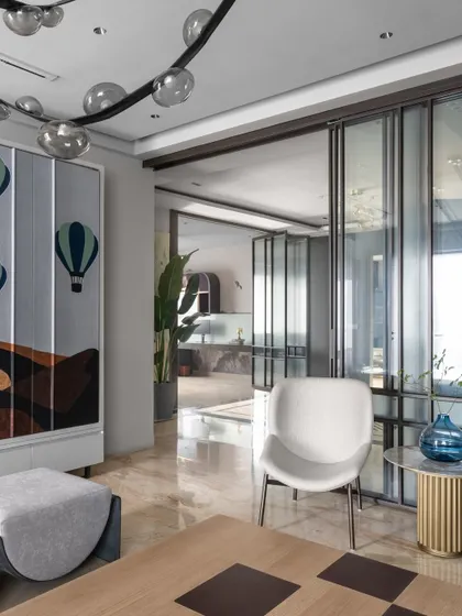 This shot highlights the artistic elements of the living space, including a custom cabinet with a hot air balloon motif. The design seamlessly connects different zones while maintaining a unified, sophisticated aesthetic.