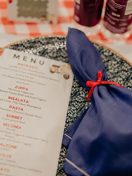 The menu for the Italian-themed gala dinner, complete with a custom illustration and a napkin tied with a simple red ribbon. Every detail was designed to enhance the 'la dolce vita' experience.