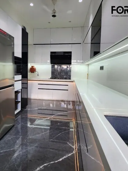 A wide perspective of a high-gloss white kitchen, showing how the reflective surfaces and integrated lighting can make a space feel larger and brighter. The black marble floor adds a grounding, luxurious element.