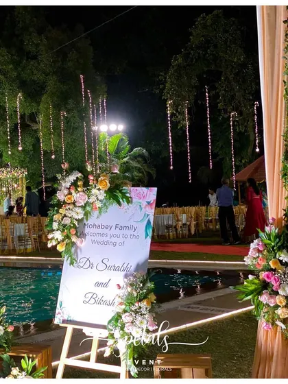 The welcome board for the Jayamala ceremony is a floral enchantment in itself. Surrounded by vibrant flowers and set against a backdrop of twinkling lights by the pool, it beckons guests to a night of celebration.