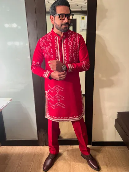 A confident pose in a striking red kurta set. The detailed white embroidery gives it a sharp, elegant look perfect for a festive evening.
